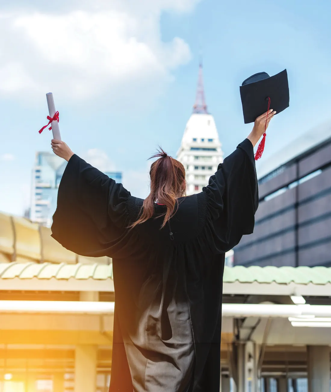 A graduate celebrating with her degree and cap